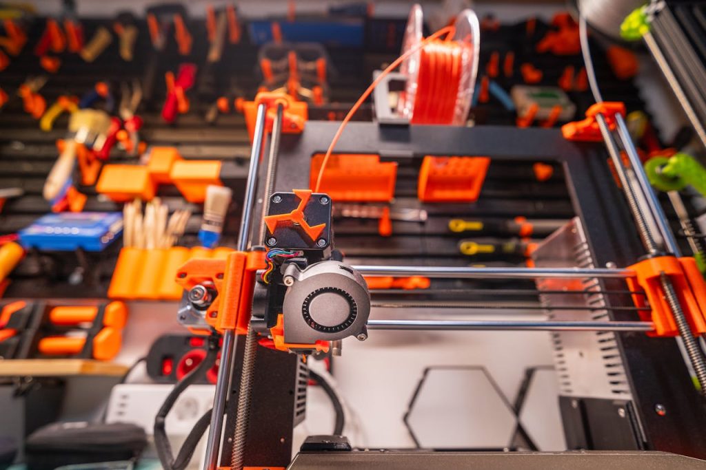 pexels-photo-20341728 Detailed view of a 3D printer with filament and tools in a workshop setting.